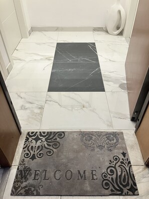 A tiled floor with a welcome mat at the entrance.