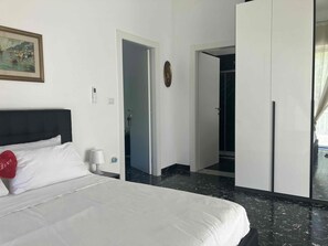 A hotel room with a bed, a bedside table, a nightstand, a door, and a wardrobe.