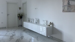 A hallway with a white console table, marble flooring, and a painting on the wall. - B&B mare mio - the warmth of home (Pescara)