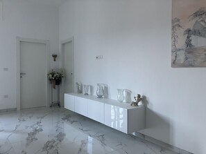 A hallway with a white console table, marble flooring, and a painting on the wall. - B&B mare mio - the warmth of home (Pescara)
