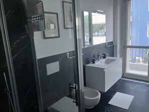 A modern bathroom with a glass shower enclosure, a toilet, a sink, and a bathtub. - B&B mare mio - the warmth of home (Pescara)