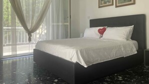 A bedroom with a bed, a window with sheer curtains, and two framed pictures on the wall. - B&B mare mio - the warmth of home (Pescara)