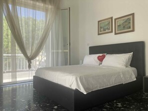 A bedroom with a bed, a window with sheer curtains, and two framed pictures on the wall. - B&B mare mio - the warmth of home (Pescara)