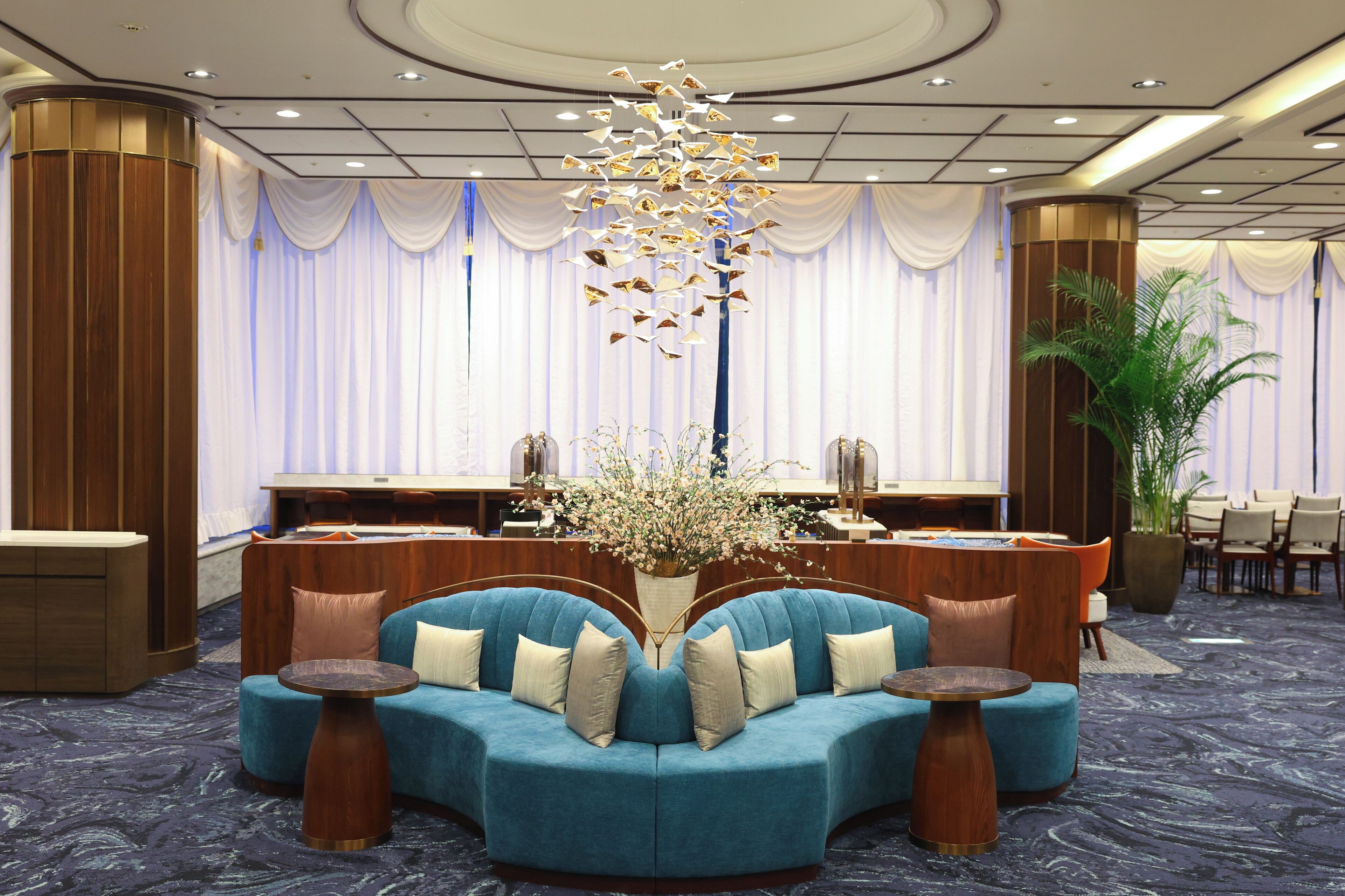 A hotel lobby with a blue sofa set, a reception desk, and a decorative plant.