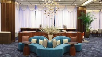 A hotel lobby with a blue sofa set, a reception desk, and a decorative plant.