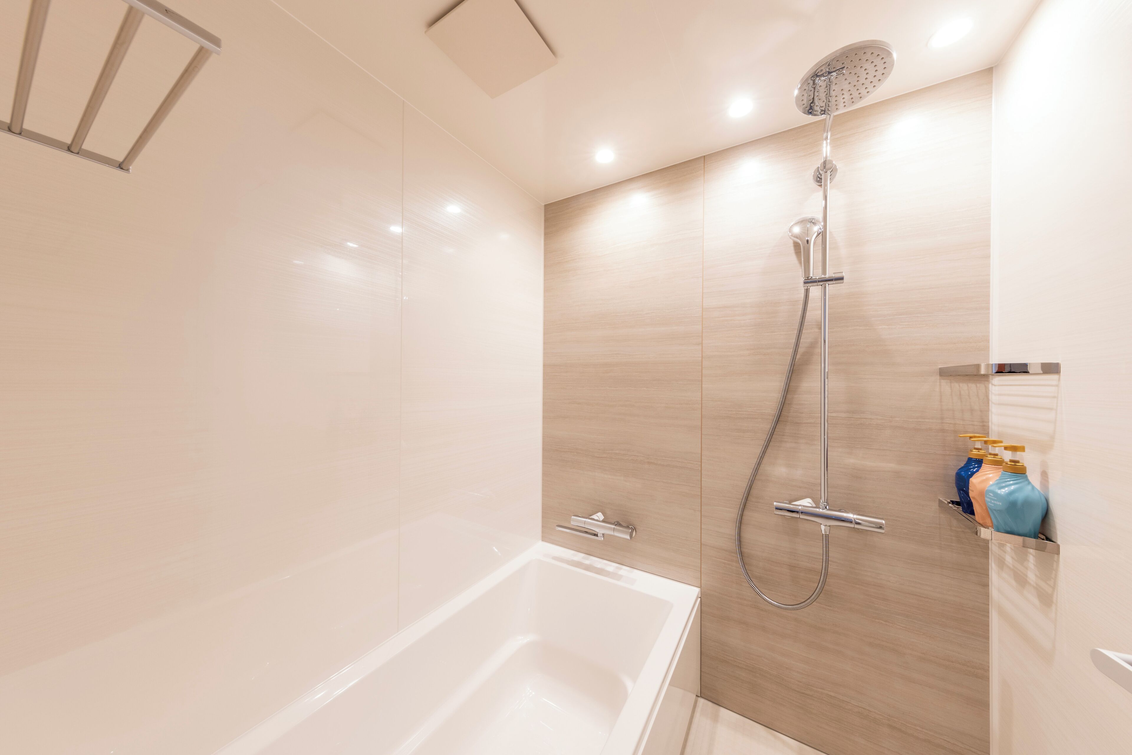 Un baño moderno con bañera, ducha con cabezal de ducha manual y toallero de pared.