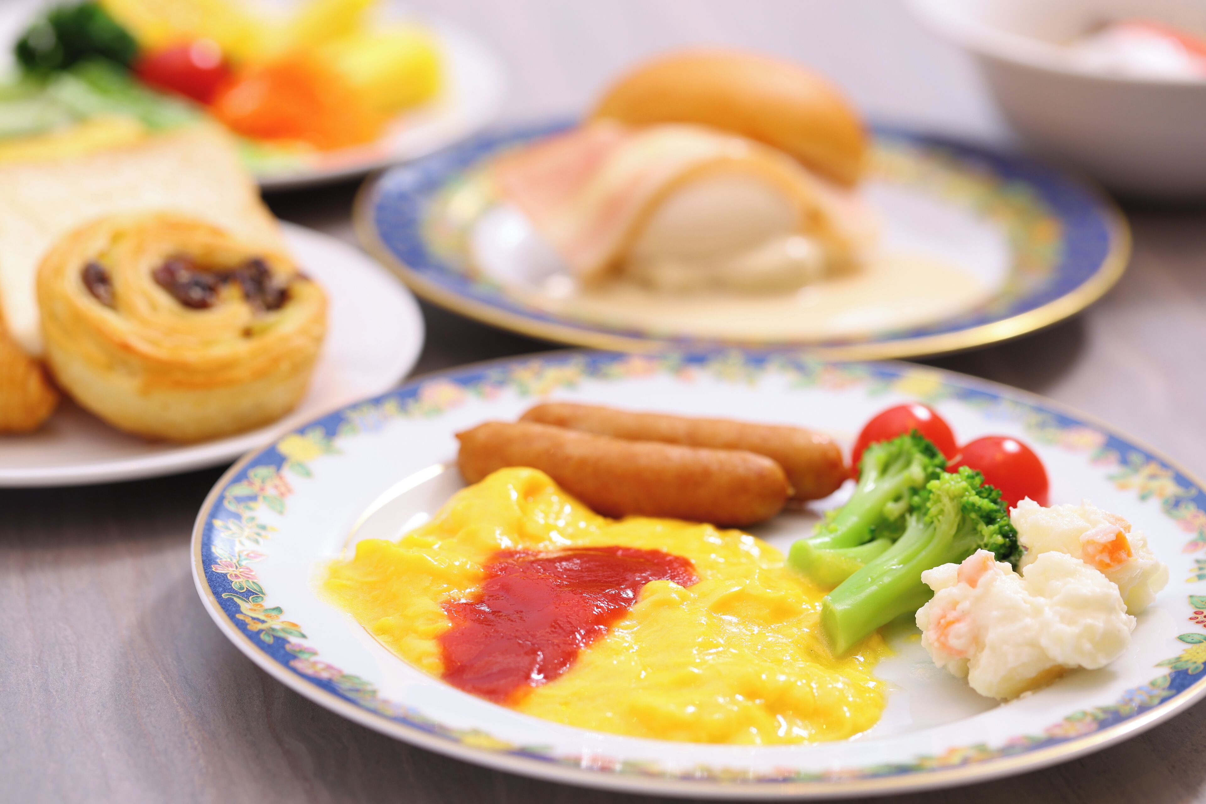 A plate with scrambled eggs, ketchup, broccoli, and a sausage.