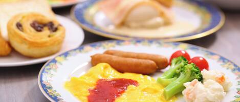 A plate with scrambled eggs, ketchup, broccoli, and a sausage.