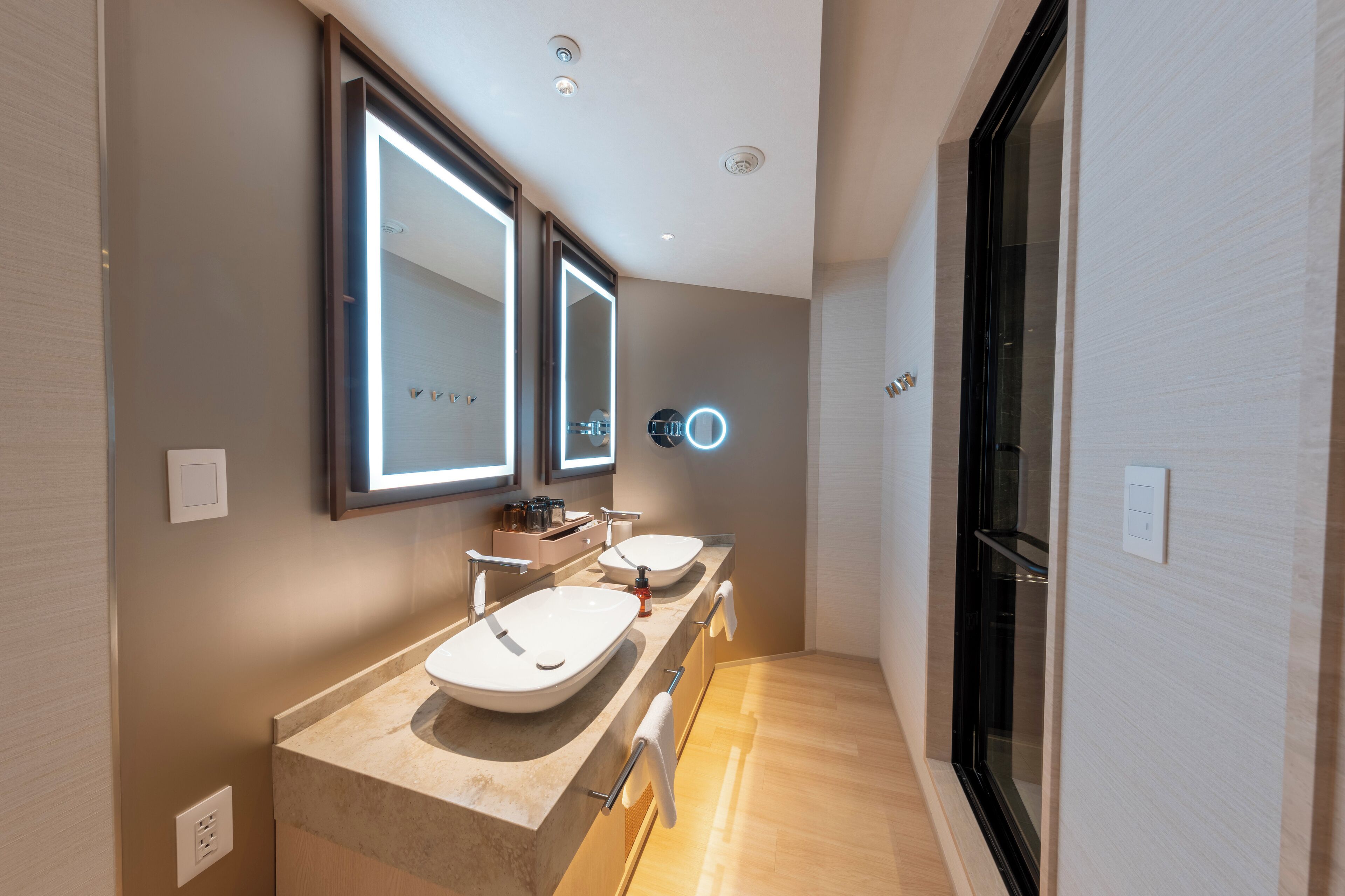 Une salle de bain moderne avec un long meuble-lavabo, deux vasques et un grand miroir.