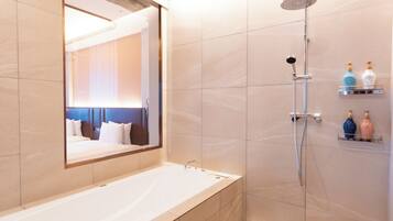 A modern bathroom with a large bathtub, a showerhead, and a mirror.