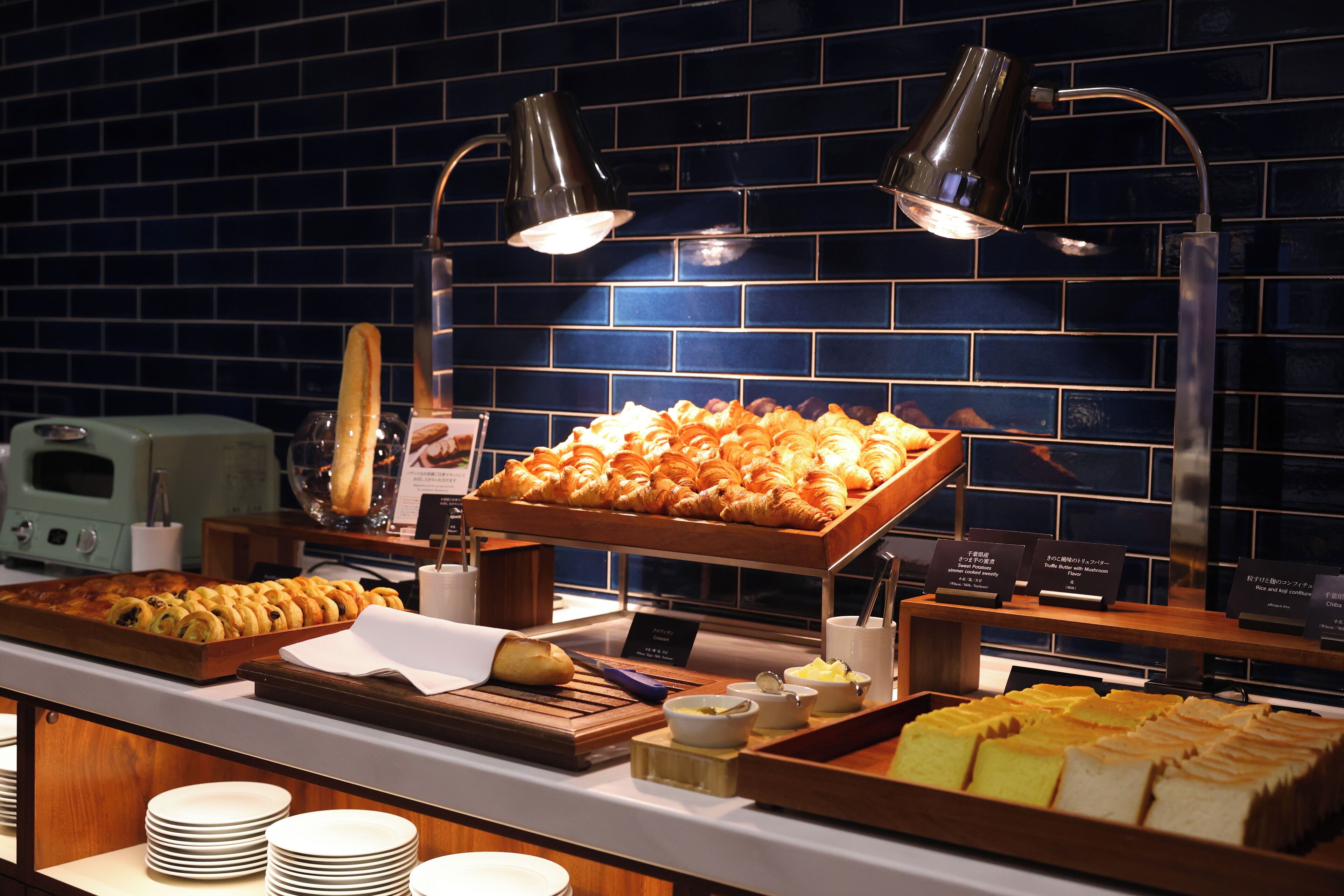 Un bufé con diversas opciones de panadería y pastelería, incluyendo croissants y pan, expuesto sobre tablas de madera.