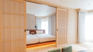 Quarto de hotel moderno com cama grande, portas deslizantes e uma pequena área de refeições.