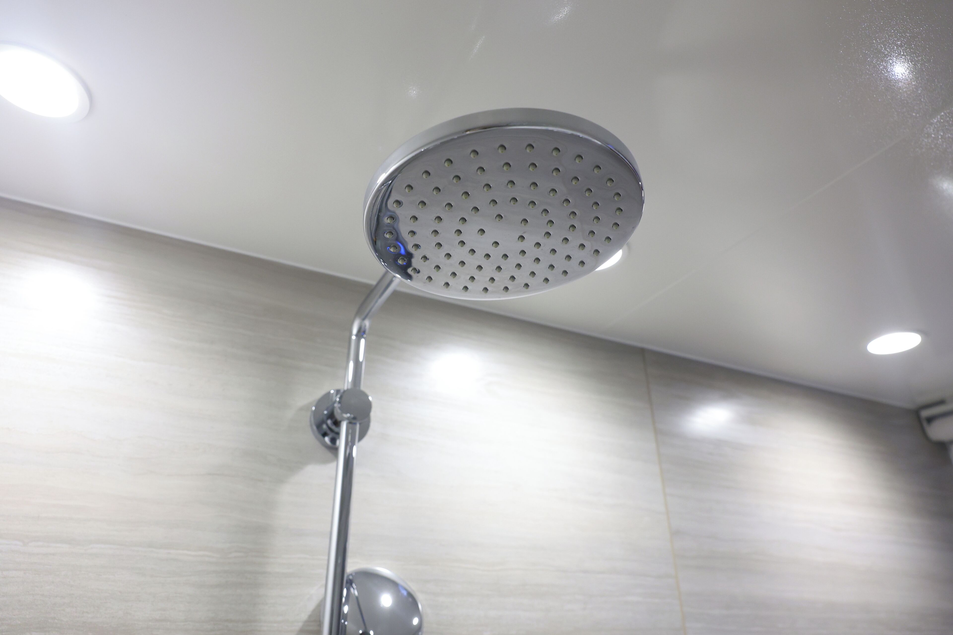 A showerhead with a circular design and multiple holes, mounted on a chrome fixture.