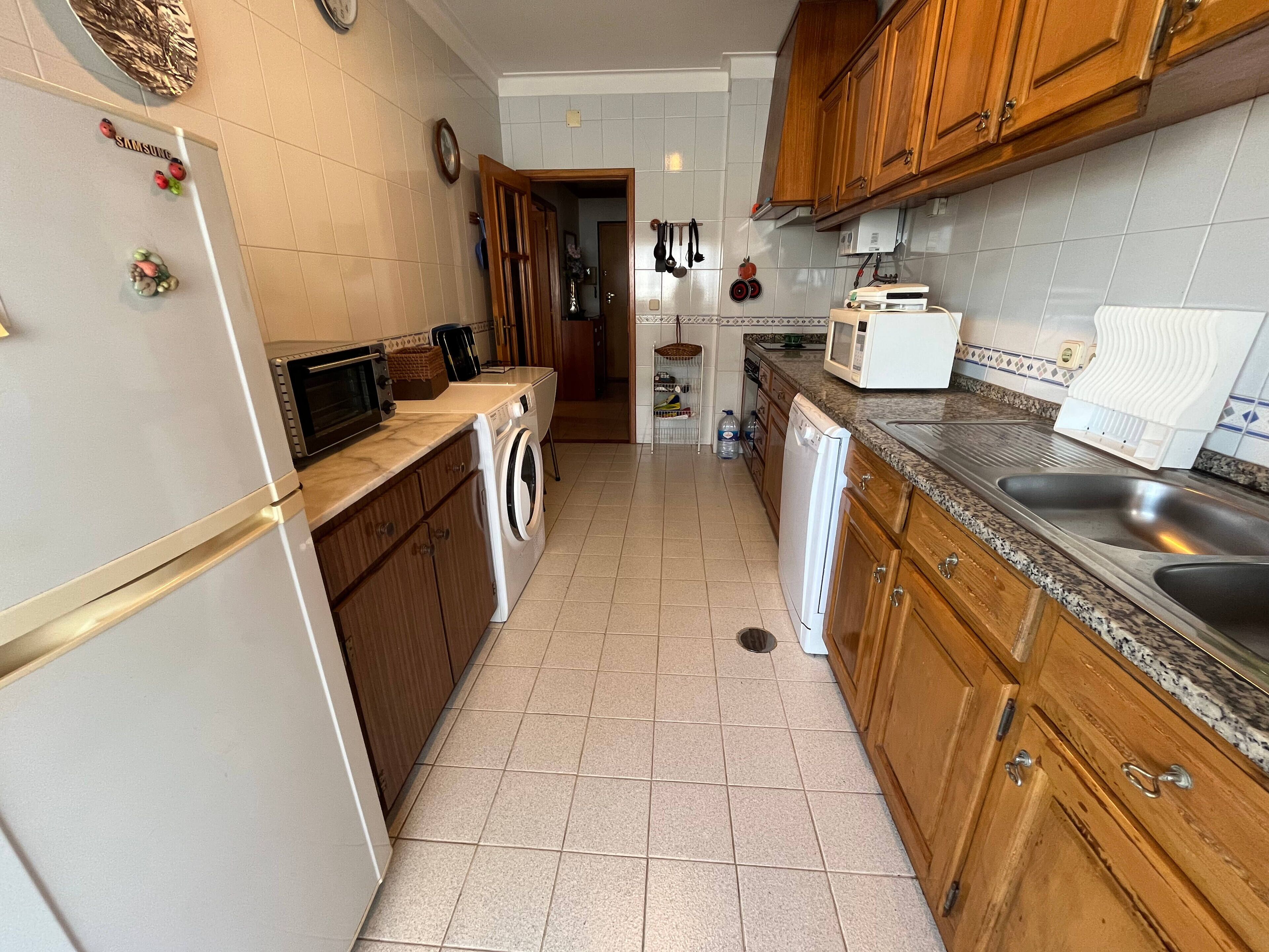 A kitchen with a washing machine, microwave, and sink.
