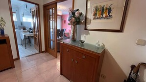 A hallway with a wooden cabinet, a framed artwork, and a vase with flowers. - Vila do Conde Beach Apartment  (Vila do Conde)