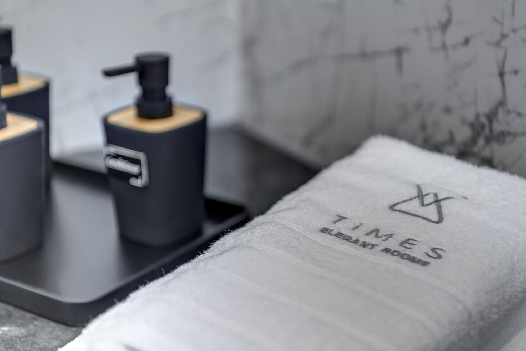 A towel with "TIMES ELEGANT ROOM" text and a black tray with a pump bottle.