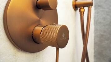 A wall-mounted shower control with a round, metallic finish and a textured knob.