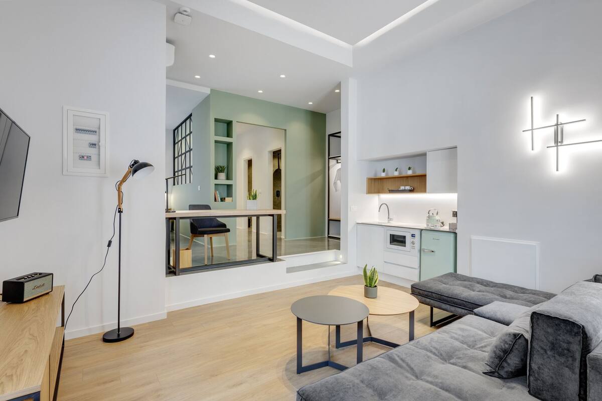 Una sala de estar moderna con un sofá gris, una mesita redonda y una lámpara de pie.