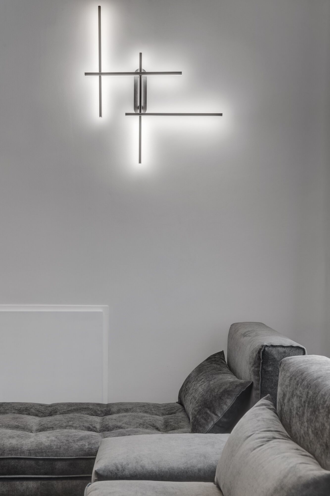 A modern living room with a sectional sofa and a minimalist wall-mounted light fixture.