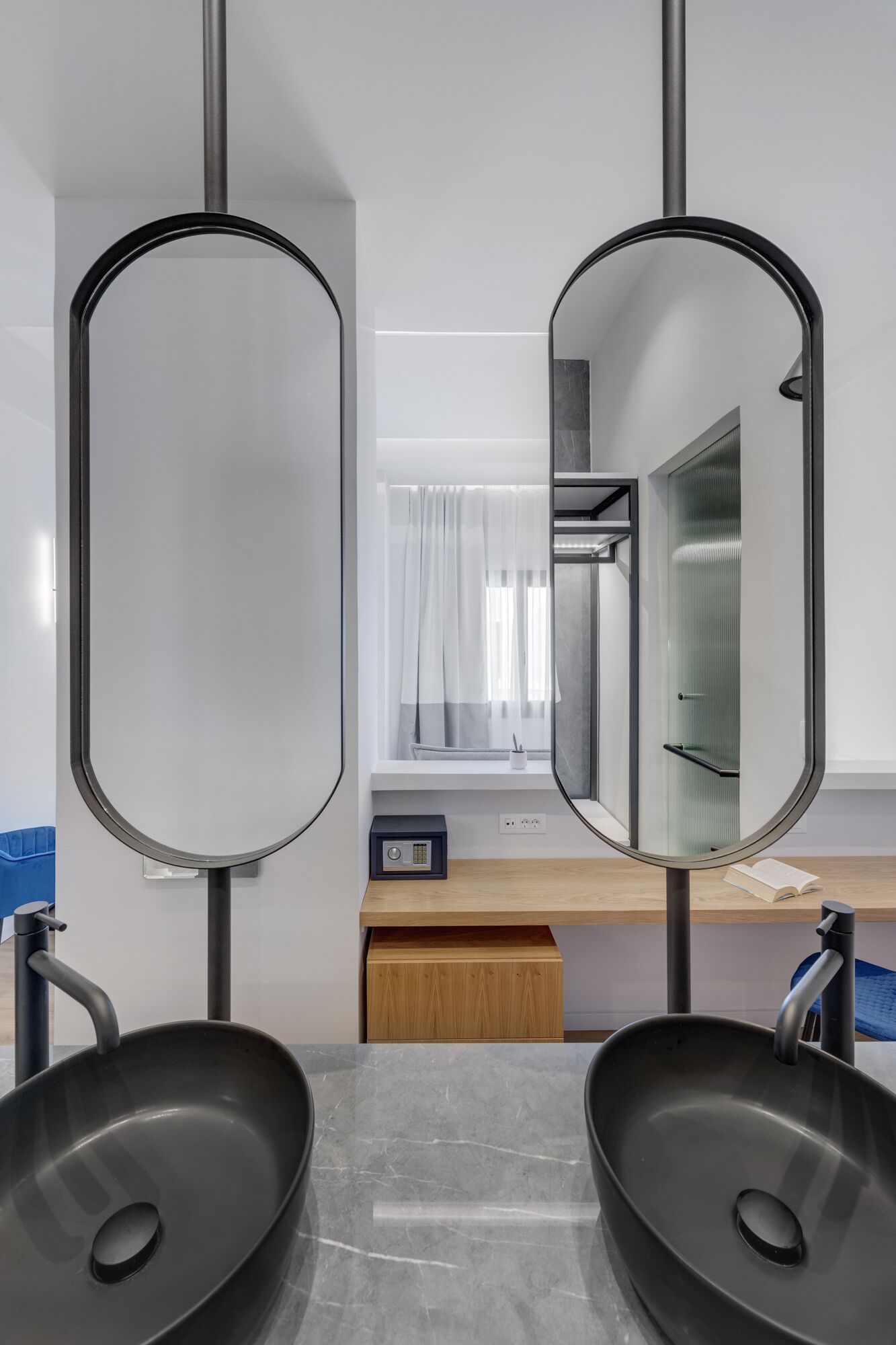 Ein modernes Badezimmer mit zwei schwarzen Waschbecken, einer Holzanrichte und einem großen Spiegel.