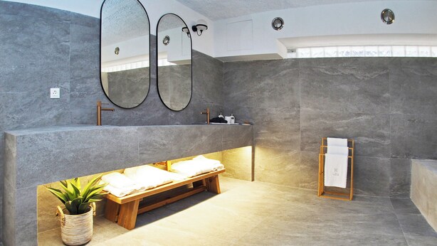 A modern bathroom with a large mirror, a wooden bench, and a towel rack. - Times Elegant Rooms (Syros)