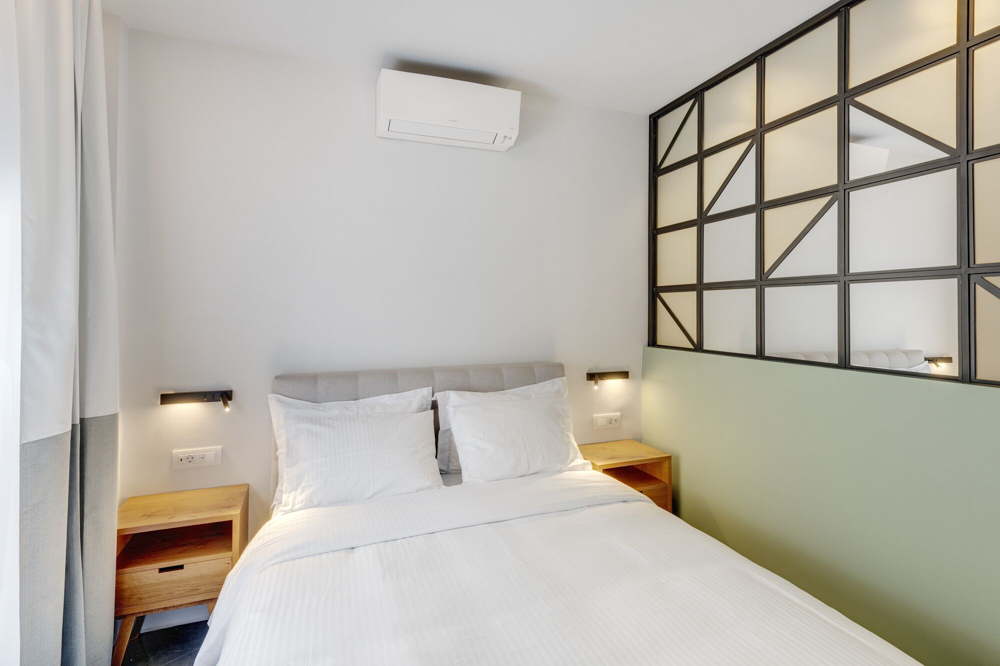 A neatly made bed with white linens, a headboard, and two bedside tables with lamps.