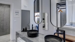 A modern bathroom with two black sinks, a large mirror, and a sleek marble countertop. - Times Elegant Rooms (Syros)
