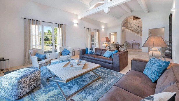 A spacious living room with a high ceiling, a staircase, and a dining area.
