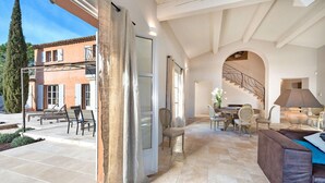 A spacious living area with a dining table, chairs, and a staircase.