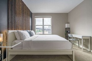 Une chambre à coucher moderne, avec un lit, une table de chevet, un bureau et une chaise.