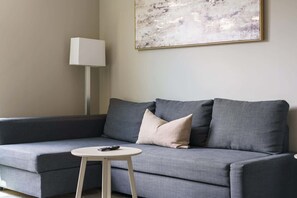 Una sala de estar moderna con un sofá gris, una mesita redonda y una lámpara.