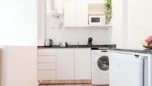 A compact kitchen with a washing machine, a microwave, and a coffee maker.