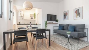 A modern living room with a sofa, coffee table, and dining area with chairs.