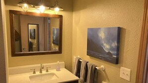 Une salle de bain avec un lavabo blanc, un miroir et un porte-serviettes.