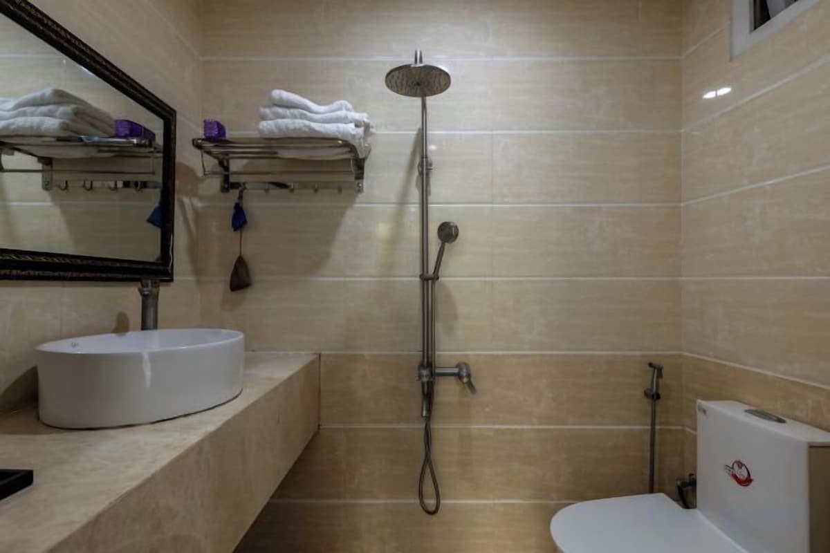 A bathroom with a sink, mirror, towel rack, shower, and toilet.
