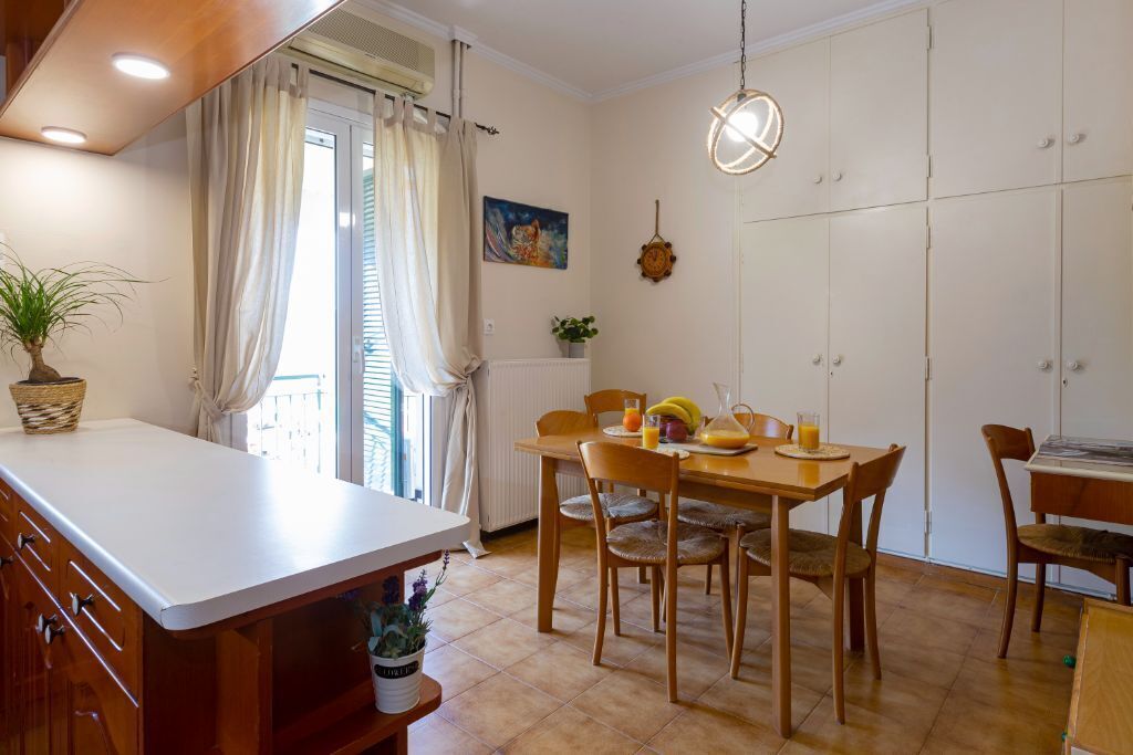 A dining area with a wooden table and chairs, a potted plant, and a hanging light fixture.