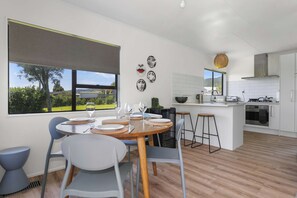 Una cucina moderna con mobili bianchi, un'isola centrale e un'area pranzo con un tavolo rotondo e sedie.