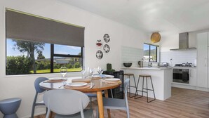 Una cocina moderna con armarios blancos, una isla central y una zona de comedor con una mesa redonda y sillas.