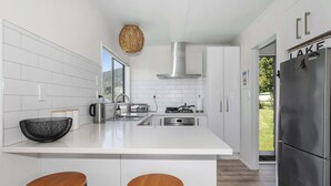 Una cocina moderna con armarios blancos, un refrigerador de acero inoxidable y dos taburetes de madera.