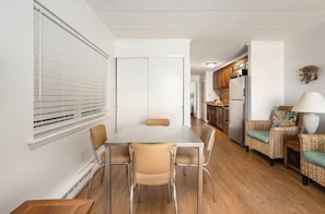 Een moderne keuken met houten kastjes, een koelkast en een eethoek met een tafel en stoelen.