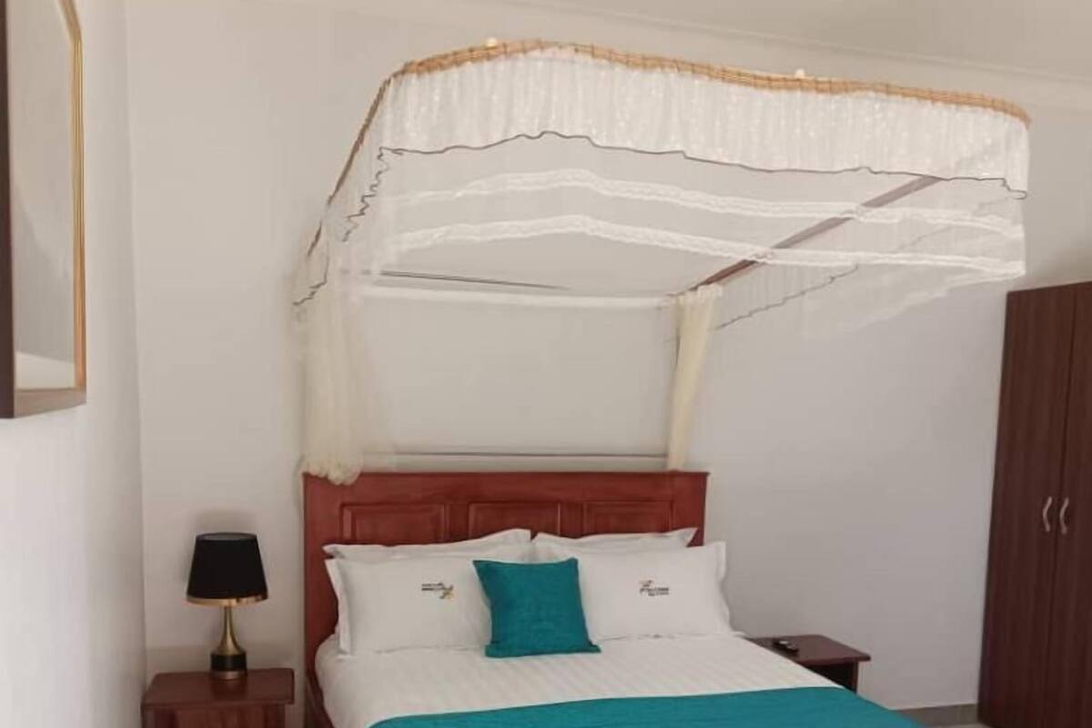 A bedroom with a wooden bed, a nightstand with a lamp, and a wardrobe.