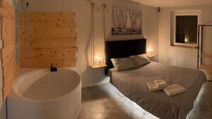 Ein Schlafzimmer mit einem großen Bett, einer Holzwand, einer Badewanne und einem Gemälde über dem Bett.