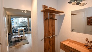 Una habitación moderna con un armario de madera, una pequeña mesa con sillas, un espejo y vistas al balcón exterior.