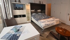 Un dormitorio con cama, escritorio con silla, televisor y armario.