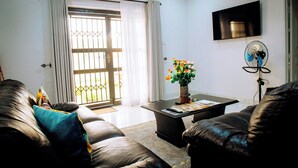 A living room with a sofa, a coffee table, and a TV mounted on the wall. - Luxury 2 Bed Self Catering Apartment in Masvingo (Masvingo)