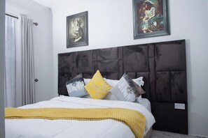 Un dormitorio con una cama grande, un cabecero y dos cuadros en la pared.