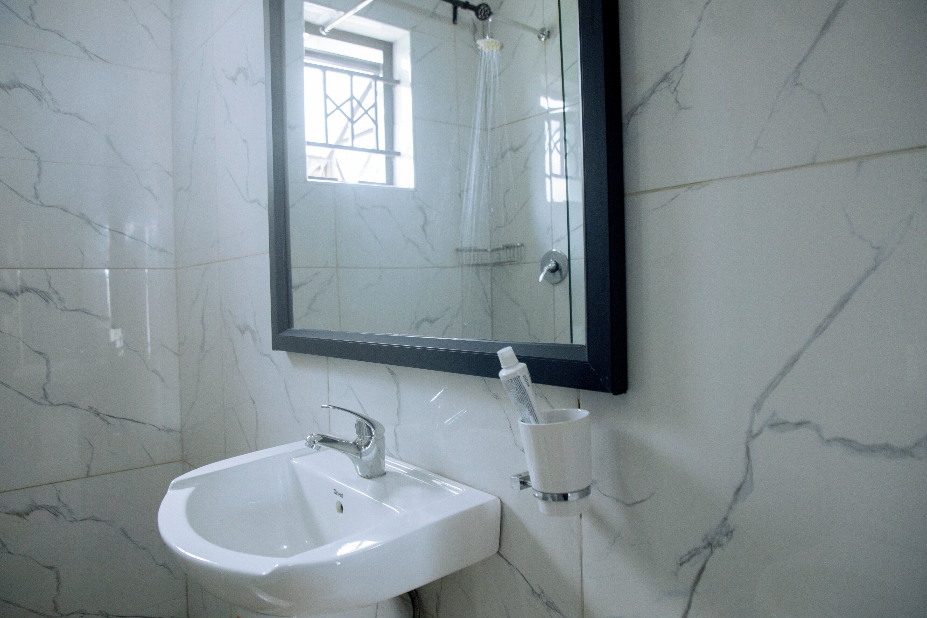 A bathroom with a white sink, a mirror, and a toothbrush holder.