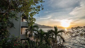 Un edifici modern amb un balcó que domina un tramunt a la mar, envoltat de vegetació tropical.