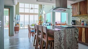 A modern kitchen with a large island, wooden cabinets, and a view to the outside.
