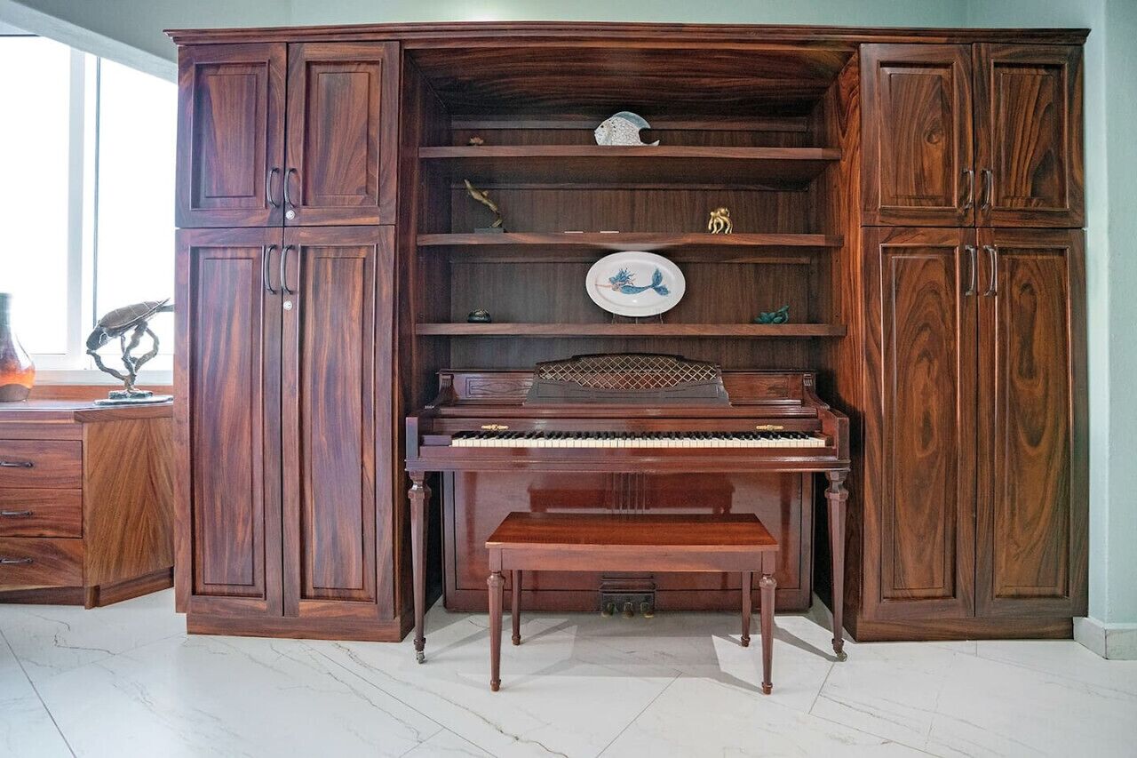 A grand piano in a spacious room with wooden cabinets and shelves.